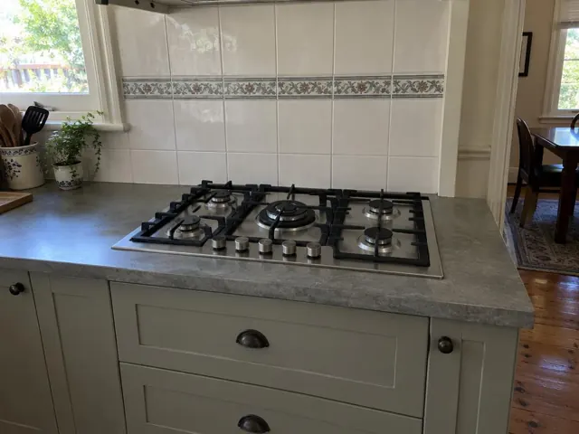 Gas cooktop set into a grey benchtop with tiled splashback in a home kitchen in Farley